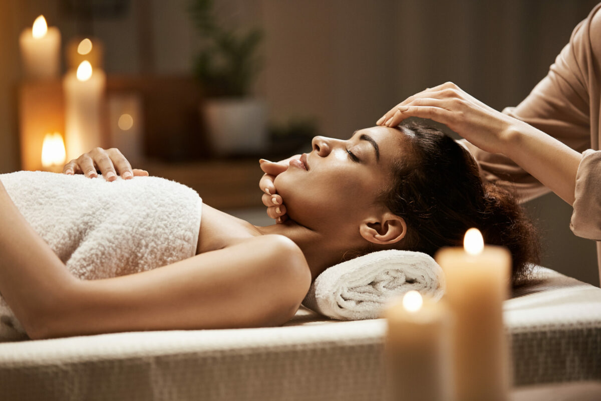 Une femme profite d'un massage du visage dans un salon de spa. Yeux fermés.